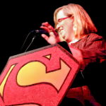 photo of Jenn Burleton standing at a podium behind a Supergirl sign.