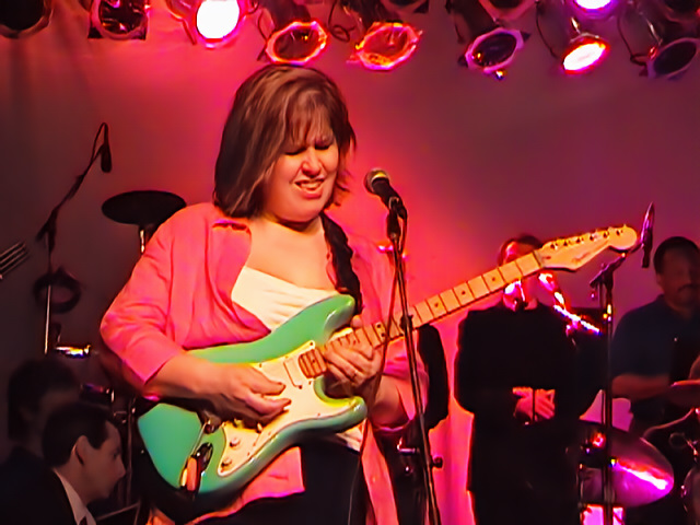 Jenn Burleton onstage playing lead guitar