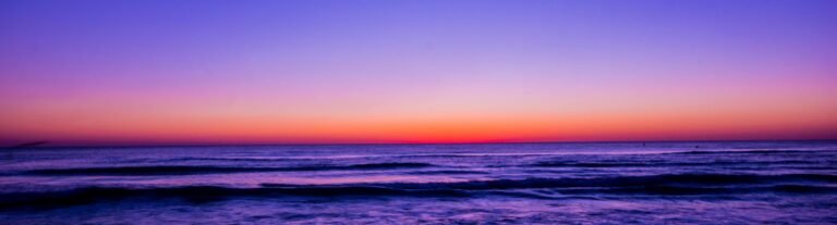Serene beach sunset with vibrant colors reflecting on the water and waves.