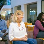 Multiethnic group of students with teacher sitting on chairs in classroom and attentively listening at presentation