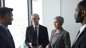 Group of business professionals in a formal meeting setting discussing strategy indoors.